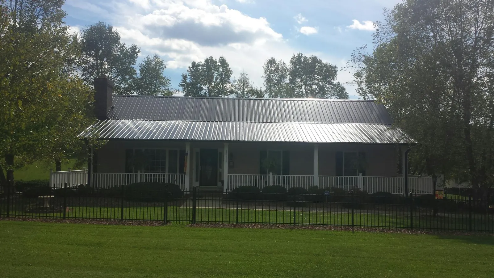 Gray metal roof on a brick ranch with a full width front porch — Gutter Guard Installation work by our crew in Spring Hill